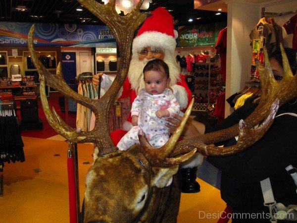 Baby Sitting On Reindeer With Santa